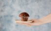 photo of person holding a plate of chcolate muffin